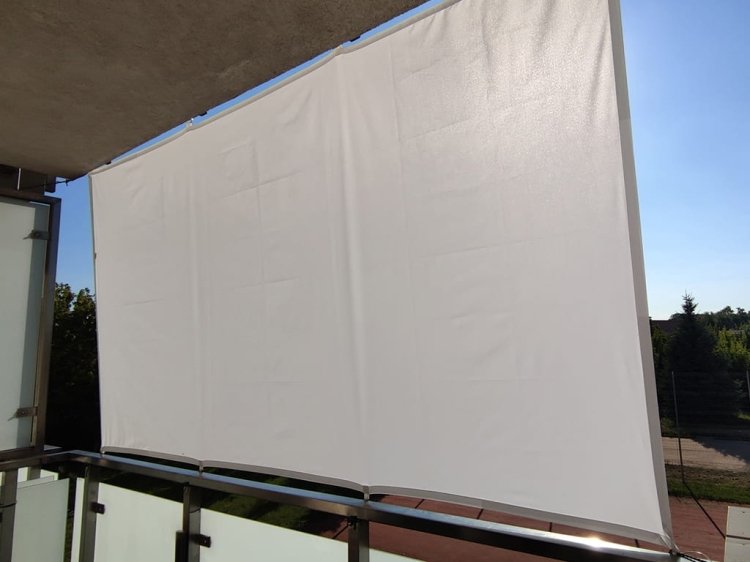 Wit, rechthoekig schaduwdoek gemonteerd op het balkon als verticale bescherming tegen zon en regen