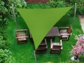 Voile d'ombrage triangulaire verte au-dessus d'un salon de jardin en bois sur une pelouse