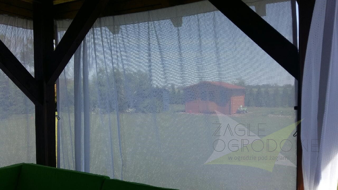 Cortina de terraza blanca semitransparente que protege del sol el interior de un cenador de madera para jardín
