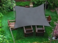 Voile d'ombrage carrée grise 3x3 m installée au-dessus de meubles en bois sur une pelouse verte