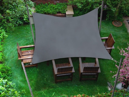 Voile d'ombrage carrée grise 3x3 m installée au-dessus de meubles en bois sur une pelouse verte