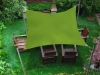 Vela de sombra rectangular verde 3x4 m sobre un conjunto de muebles de madera en el jardín, fijada a postes