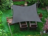 Vela ombreggiante grigia 4,2x4,7 m montata sopra un set di mobili da giardino in legno sul prato