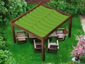 Vela da giardino verde impermeabile e retrattile su una pergola in legno con mobili da giardino.