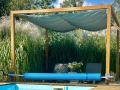 Vela ombreggiante impermeabile scorrevole 2,5x3 m color mare, montata su una pergola in legno sopra la piscina
