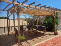 Store romain de terrasse beige 2,5x3 m monté sur une pergola en bois au-dessus d'un salon de jardin