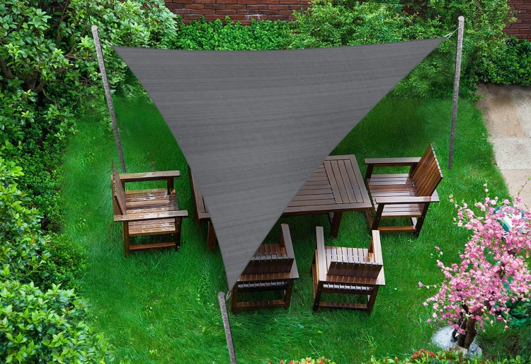 Szary trójkątny żagiel przeciwsłoneczny 5x5x7 m z tkaniny HDPE nad drewnianym zestawem mebli ogrodowych na trawie