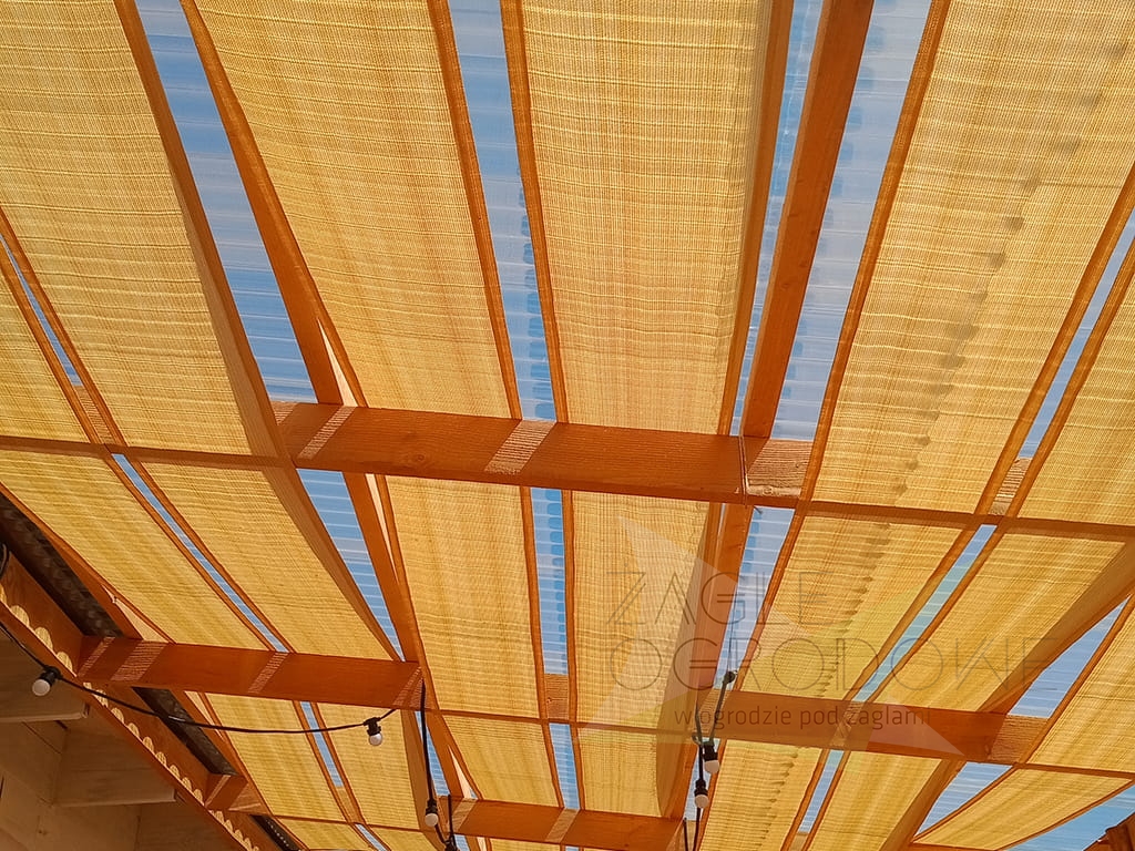 Toldo tipo vela dorado de tejido HDPE montado sobre una estructura de madera para techado de terraza