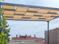 Bandes de pavillon beiges en tissu HDPE montées sur une pergola de terrasse en métal offrant de l'ombre