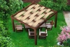 Brązowa pergola w ogrodzie z przeplatanymi kremowymi pasami przeciwsłonecznymi z tkaniny HDPE nad meblami tarasowymi