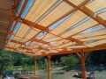 Sandfärgat HDPE-solskyddsbälte måttbeställt monterat under taket på en träpergola i trädgården
