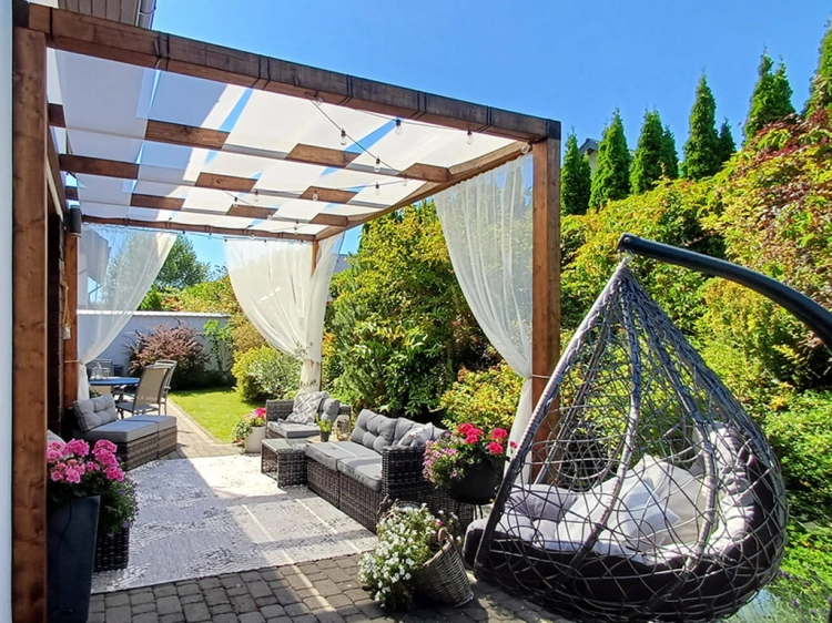 Bande Pare-soleil blanche pour pavillon montée sur une pergola en bois au-dessus d'une terrasse avec mobilier de jardin