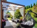 Wit zonnezeil voor overkappingen gemonteerd op een houten pergola boven een terras met tuinmeubelen