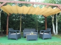 Beiges Raffrollo aus HDPE als Sonnenschutz an einer Holzpergola über Gartenmöbeln montiert