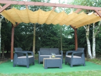Estor romano de protección solar beige de HDPE montado en una pérgola de madera sobre un conjunto de muebles de jardín