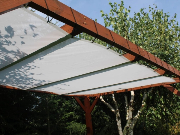 Wit zonnezeil gemonteerd op een houten pergola in de tuin