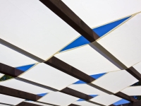 Witte zonneplans op maat gemonteerd op een houten pergola onder een blauwe lucht