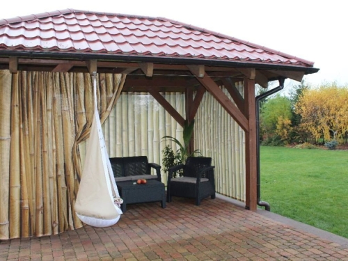 Rideau de jardin sur mesure avec impression imitation bambou installé dans un belvédère en bois avec mobilier de détente