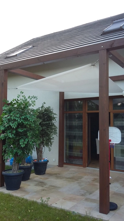 Weißes quadratisches Sonnensegel an einer Holzkonstruktion über der Terrasse am Haus montiert