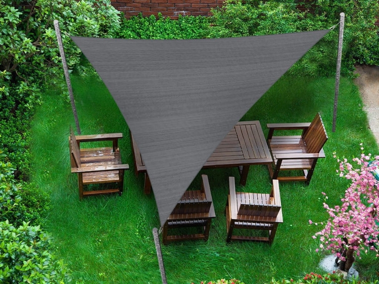 Szary trójkątny żagiel przeciwsłoneczny 4,2x4,2x5,9 m nad drewnianymi meblami ogrodowymi na trawniku