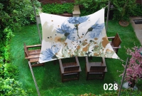 Voile d'ombrage imperméable avec imprimé floral bleu au-dessus de chaises en bois sur la pelouse