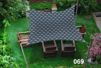 Voile d'ombrage imperméable 3x4,5 m avec motif à chevrons au-dessus d'un salon de jardin en bois sur la pelouse