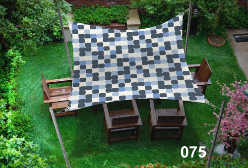 Voile d'ombrage bleu-gris à motifs 3x4,5 m déployée au-dessus de chaises en bois dans un jardin ensoleillé