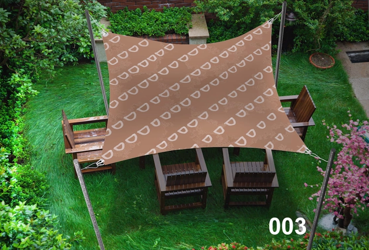 Voile d'ombrage marron avec motif blanc suspendue au-dessus de meubles en bois sur une pelouse de jardin