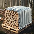 Telone bianco su misura che copre una catasta di legna da ardere su pallet nel bosco