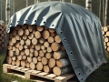Telone grigio su misura che copre una catasta di legna da ardere su un pallet nel bosco