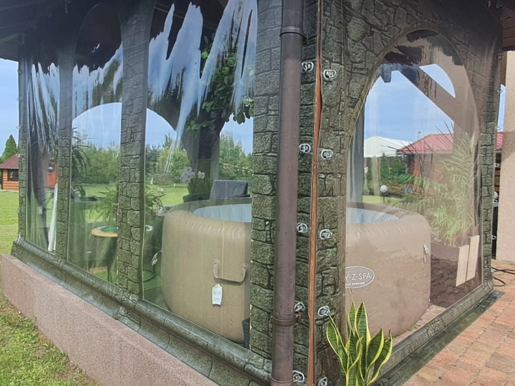 Bâche de terrasse transparente avec imprimé muret protégeant un spa de jardin rond sous un toit