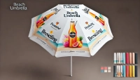 Witte reclameparasol met opdruk van zomerdrankje, fruit en strand, met kleurmonsters ernaast.