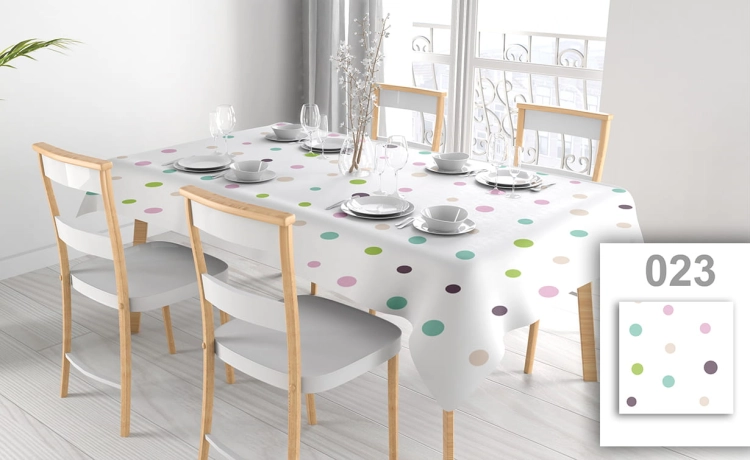 Wit vlekbestendig tafelkleed met gekleurde stippen op een eettafel met vier stoelen en elegant servies