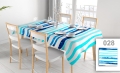 Vlekafstotend reclametafelkleed met blauwe strepen op een eettafel met witte stoelen en servies bij het raam