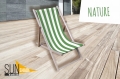Reclame ligstoel met groen-wit gestreepte opdruk op een houten frame, geplaatst op een houten terras