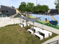 Voiles d'ombrage gris sur mesure au-dessus de tables et bancs blancs sur une aire de jeux moderne.