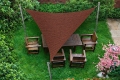 Voile d'ombrage triangulaire marron en HDPE au-dessus de meubles de jardin en bois sur une pelouse verte