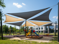 Voiles d'ombrage gris et beige au-dessus d'une aire de jeux moderne avec balançoires et toboggan sous un ciel nuageux