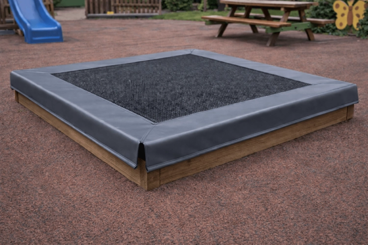 Bâche grise ajustée pour bac à sable avec filet perméable à l'eau sur une structure en bois dans un jardin