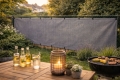 Brise-vue gris en HDPE pour clôture, protection contre le vent et l'ombre, installé dans un jardin près d'une table et d'un barbecue