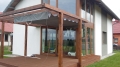 Rulou roman de terasă Premium gri 2,5x4 m montat pe o pergolă de lemn deasupra terasei la apus