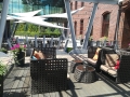 Voile d'ombrage triangulaire imperméable Premium blanc sur une terrasse de restaurant avec meubles en rotin