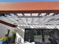 Voile d'ombrage triangulaire blanc Premium monté sous une pergola comme protection solaire sur la terrasse