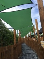 Voile d'ombrage vert imperméable 3x5 m installé sur des poteaux en bois au-dessus d'une allée