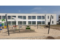 Weißes, rechteckiges Sonnensegel 3,2x2,5 m über einem Spielplatz an einem modernen Gebäude