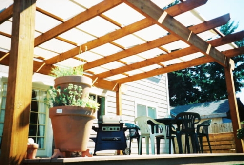 Voile d'ombrage de pavillon blanc sur structure de terrasse en bois avec meubles de jardin et barbecue