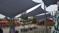 Voile d'ombrage carrée grise 3x3 m suspendue au-dessus d'une allée et d'une file d'attente dans un parc d'attractions