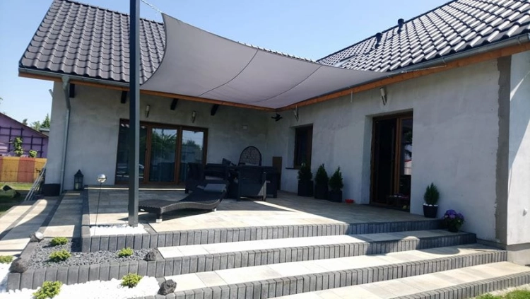 Voile d'ombrage blanche imperméable 3x4 m installée sur une terrasse avec mobilier de jardin devant une maison moderne
