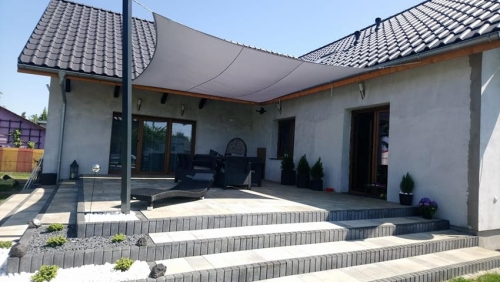Voile d'ombrage rectangulaire imperméable 3x5 m installée au-dessus de la terrasse d'une maison moderne à façade claire
