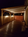 Toldo vela impermeable 4x4m instalado bajo una pérgola de madera en la terraza por la noche